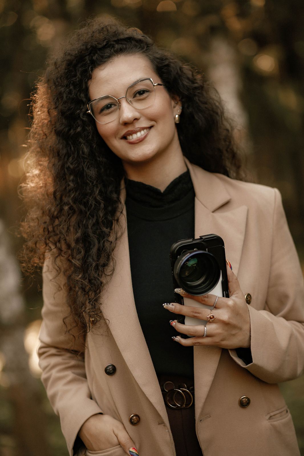 Fer Guimarães, storymaker, sorrindo segurando a câmera de celular usada nas coberturas